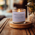 Candle labeled 'Prince of Peace' on a wooden coaster with blurred background